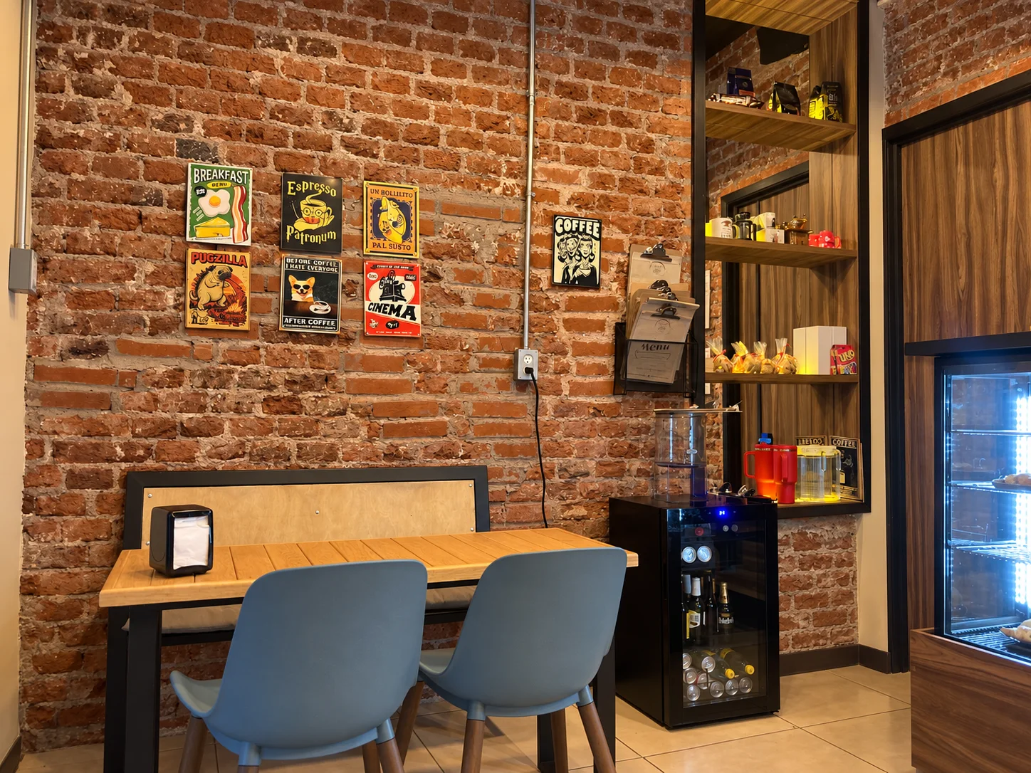 El interior de The Latte Date, con mesas de madera y una cálida pared de ladrillo